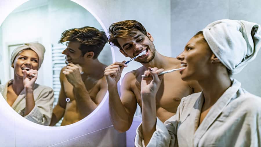 אישה עם מברשת שיניים מברשת את שינייםיה בחדר אמבטיה.