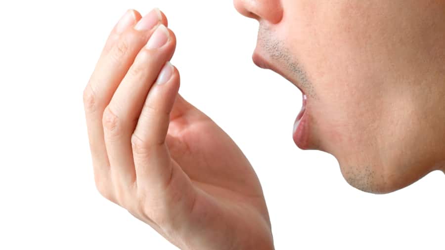 בחור מנסה להריח את הנשימה שלו בשביל להבין למה יש ריח רע מהפה