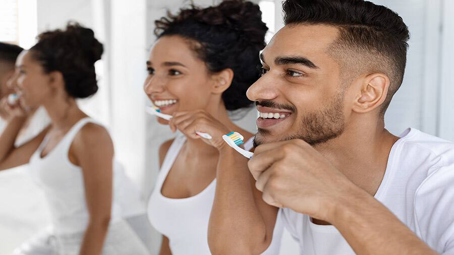 זוג צעיר ושמח מברשים שיניים ביחד בבוקר