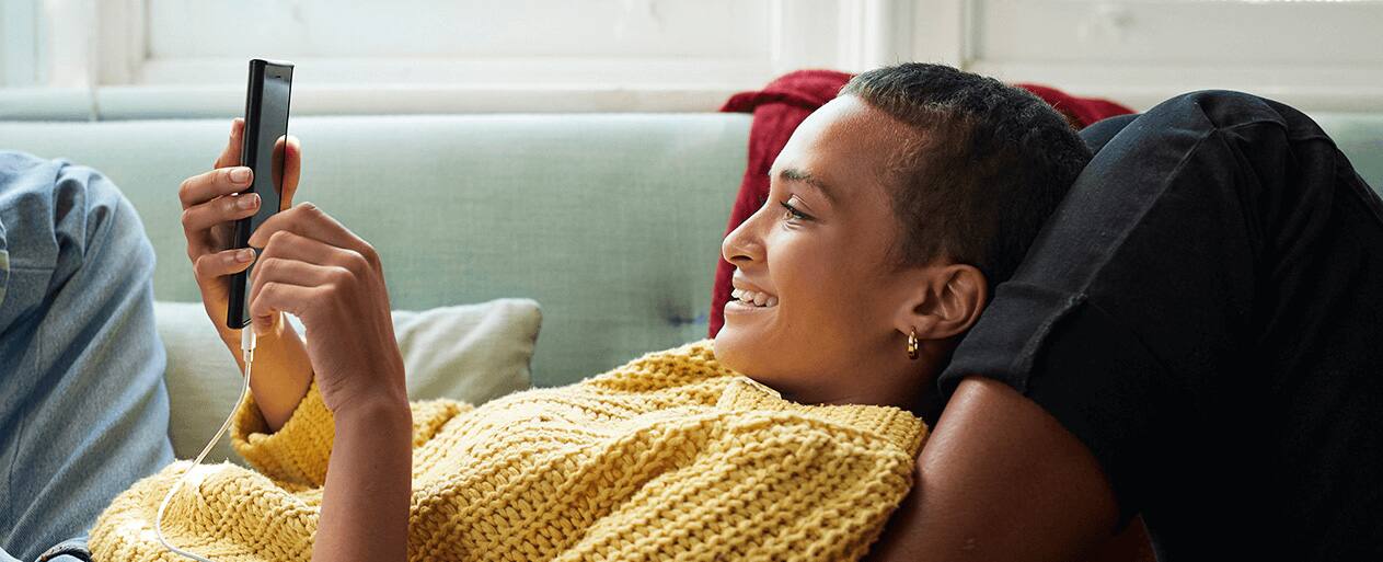 אישה שוכבת צופה בטלפון נייד